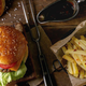 Flatlay shot of burger with sesame bun and fries on wooden background